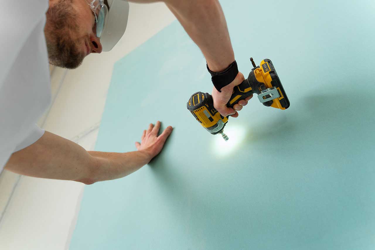 a man drilling on wall with drill machine.